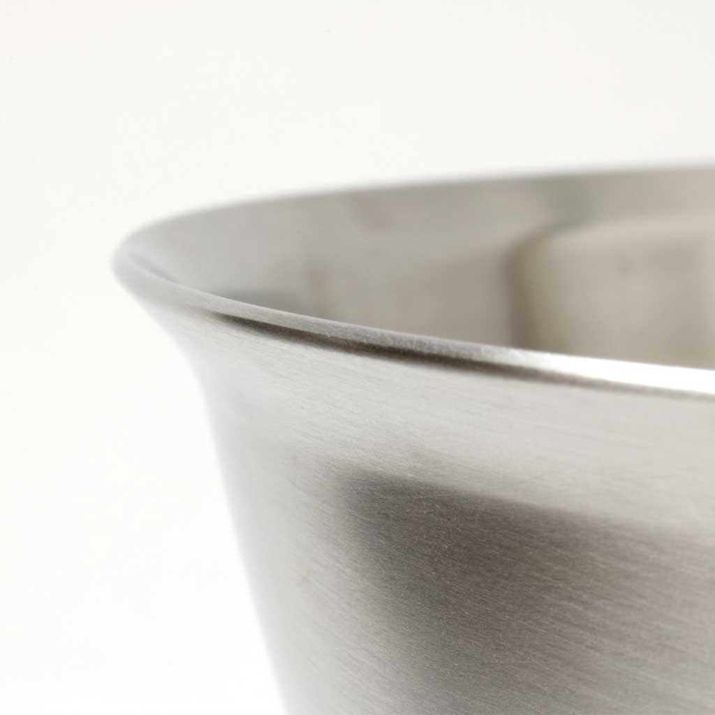 Close up of rounded edge of stainless steel bowl on white background