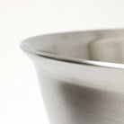 Close up of rounded edge of stainless steel bowl on white background