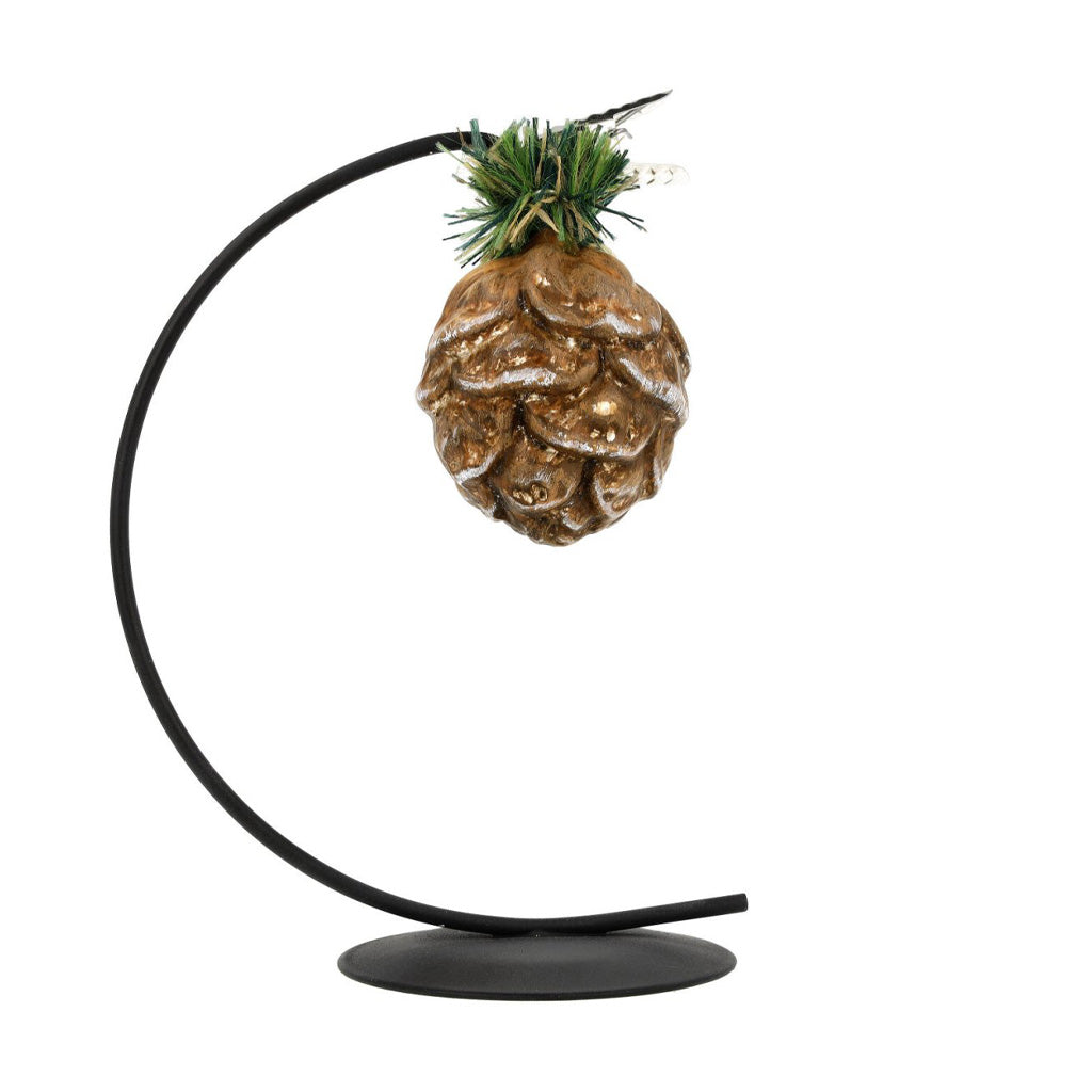A pinecone ornament hanging on black display piece.
