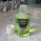 Open bottle of mouthwash with bubbles, resting on bathroom sink.