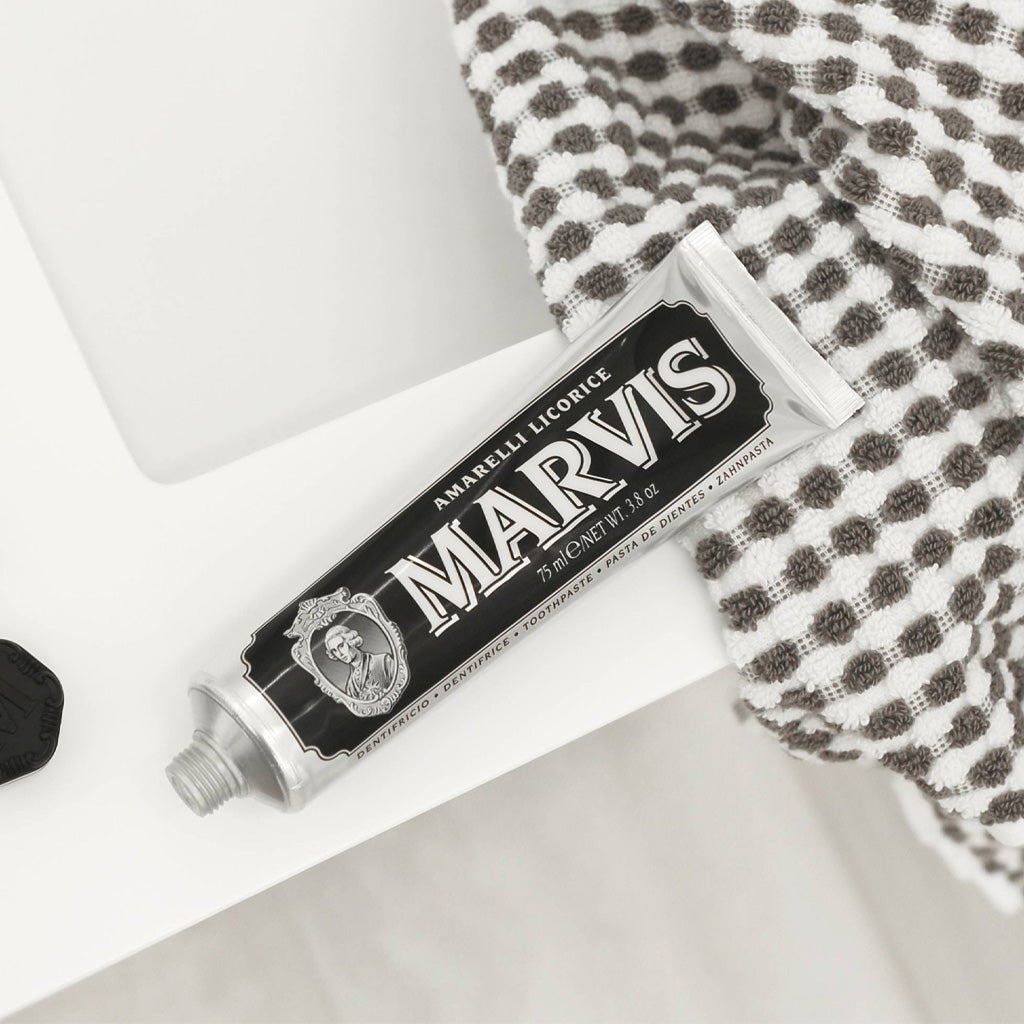 Amarelli Licorice Marvis Toothpaste tube open on bathroom sink ledge.