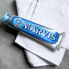 Blue Aquatic Mint Marvis toothpaste tube on top of white towel.