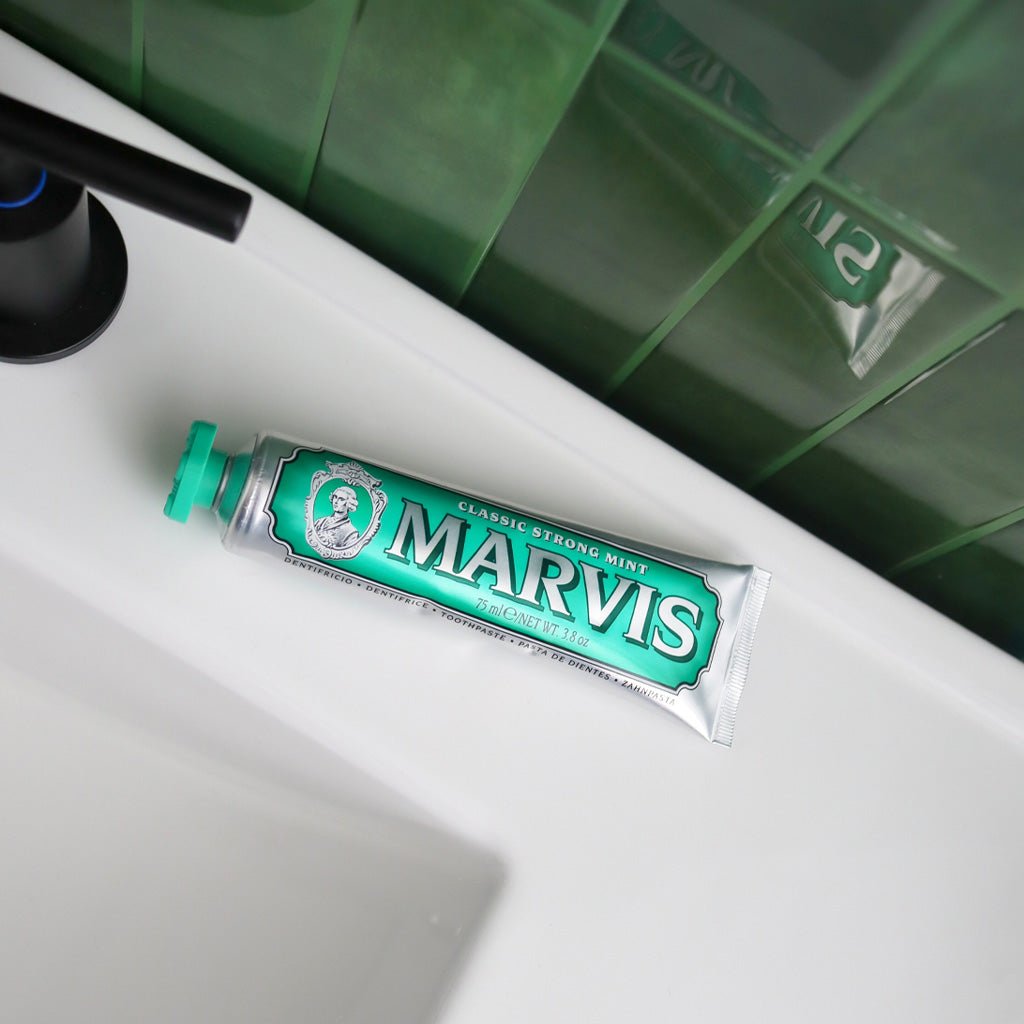 Tube of Classic Strong Mint Marvis Toothpaste on bathroom sink ledge.
