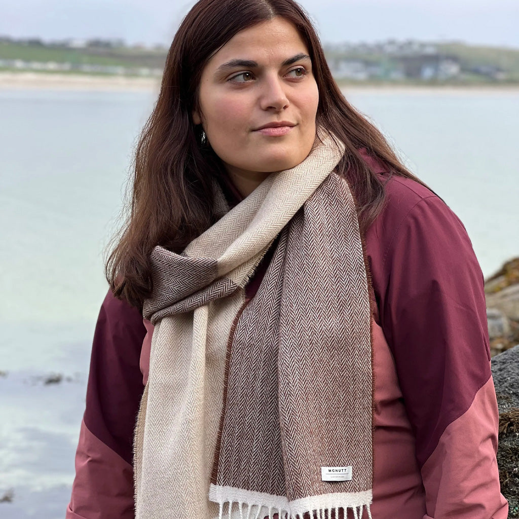 A woman wearing a beige lambswool scarf in front of natural background.