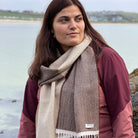 A woman wearing a beige lambswool scarf in front of natural background.