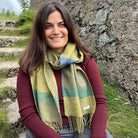 A woman wearing a green scarf in front of a natural background.