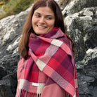 A smiling woman wearing a plaid scarf in a natural background.