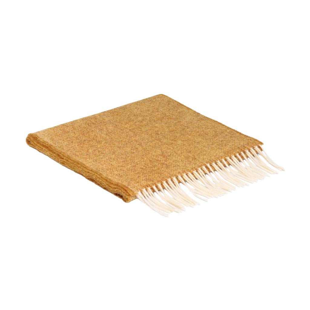 A folded woven scarf in a yellow color with white fringe.