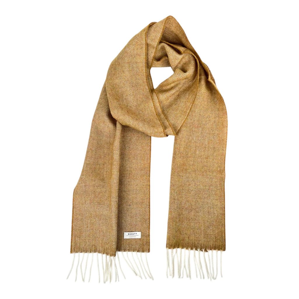 A mustard yellow woven scarf with white fringe ends displayed on a clean white background.