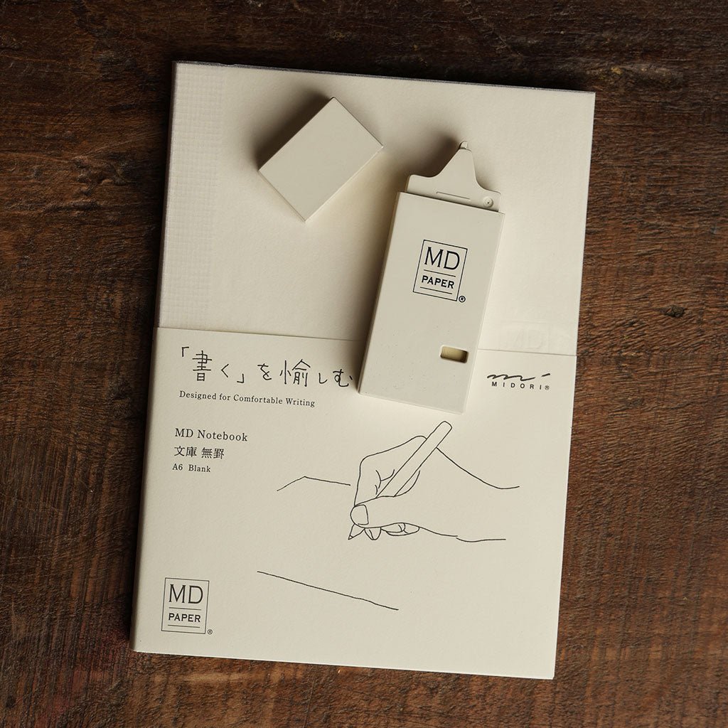 Midori cream correction tape resting on top of a Midori notebook