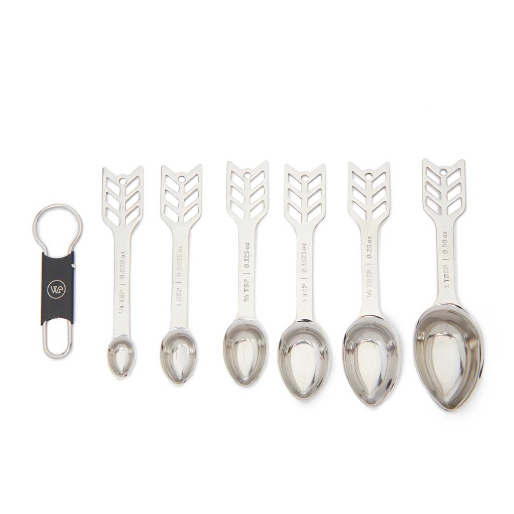 Set of six silver measuring spoons with decorative handles on a white background