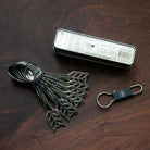 Set of metal measuring spoons with a keychain and packaging on a wooden surface