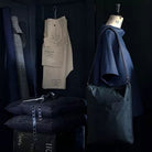 Clothing items in shades of blue, including a shirt and bag hanging on a dress form, plus pattern pieces hanging from a hook. 