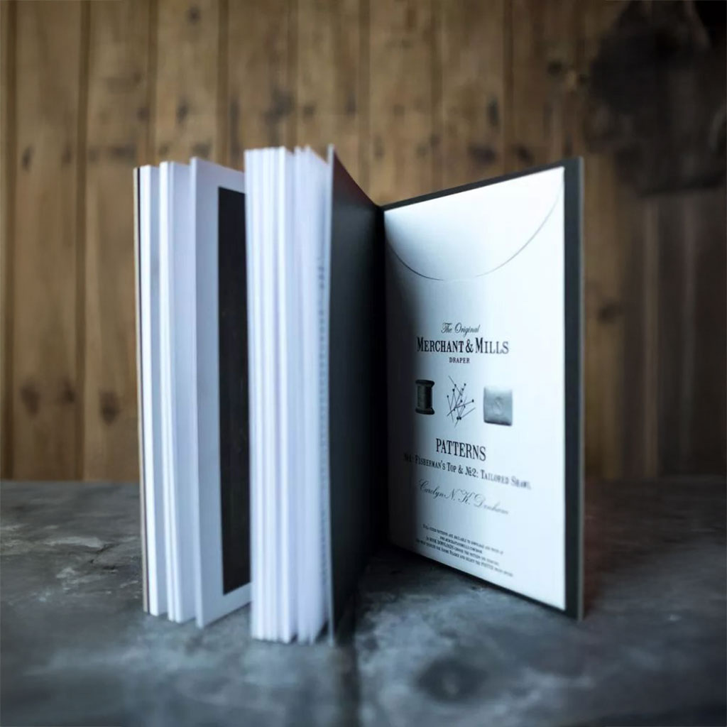 Open book showing an envelope containing patterns in the back of the book. 
