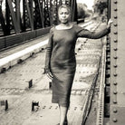 Woman wearing merchant and mills sewn clothing against city bridge background