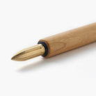 Wooden dip pen with brass nib on white surface