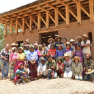 Group of people posing in front of a partially built structure
