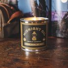 Candle in a can labeled 'Midnight Oil' on a wooden surface