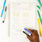 Notebook with graphic design notes, markers, and a hand holding a eraser on a white background