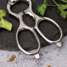 Metal kitchen shears on a dark stone surface with vegetables.
