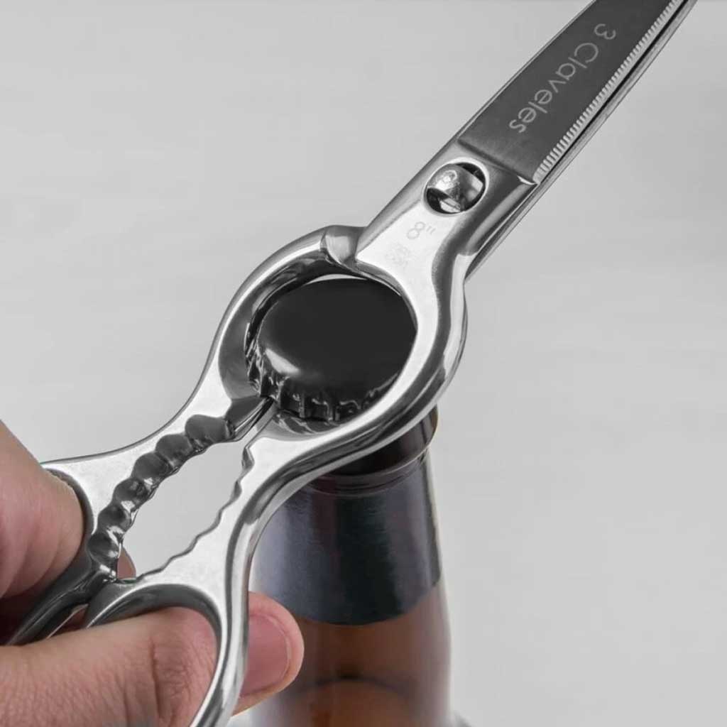 Scissors being used to open a bottle cap on a gray background