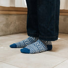 Model wearing dark wash jeans and blue jacquard wool socks.