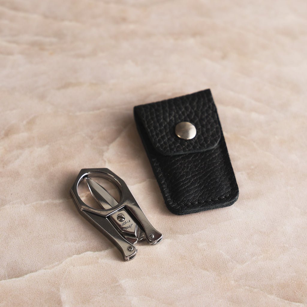 Nogent stainless steel scissors folded into a compact shape beside their black leather snap-closure case.