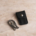 Nogent stainless steel scissors folded into a compact shape beside their black leather snap-closure case.