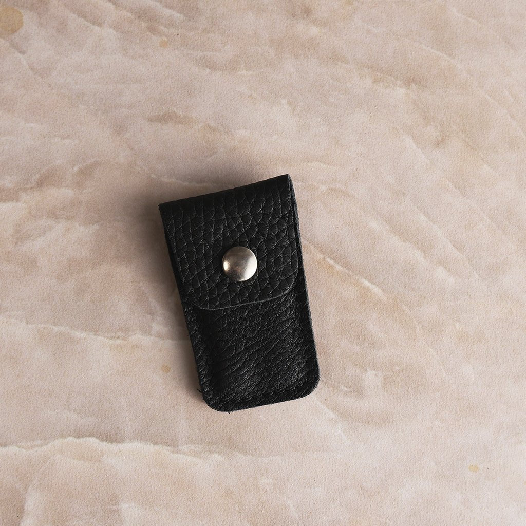 Black textured leather case for Nogent foldable scissors with a silver snap closure.