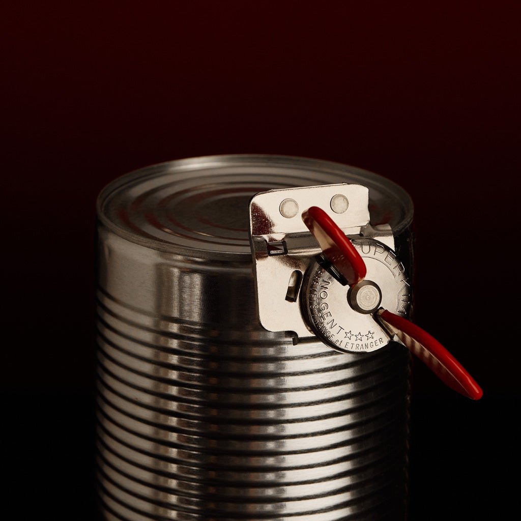 A metal can with a steel can opener with red rubber grips.