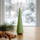 A lit sage green big candle tree on wooden table.