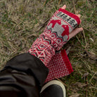 Hand wearing red wool wrist warmer with black jacket.