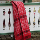 Red wool blanket draped over white and green railing.