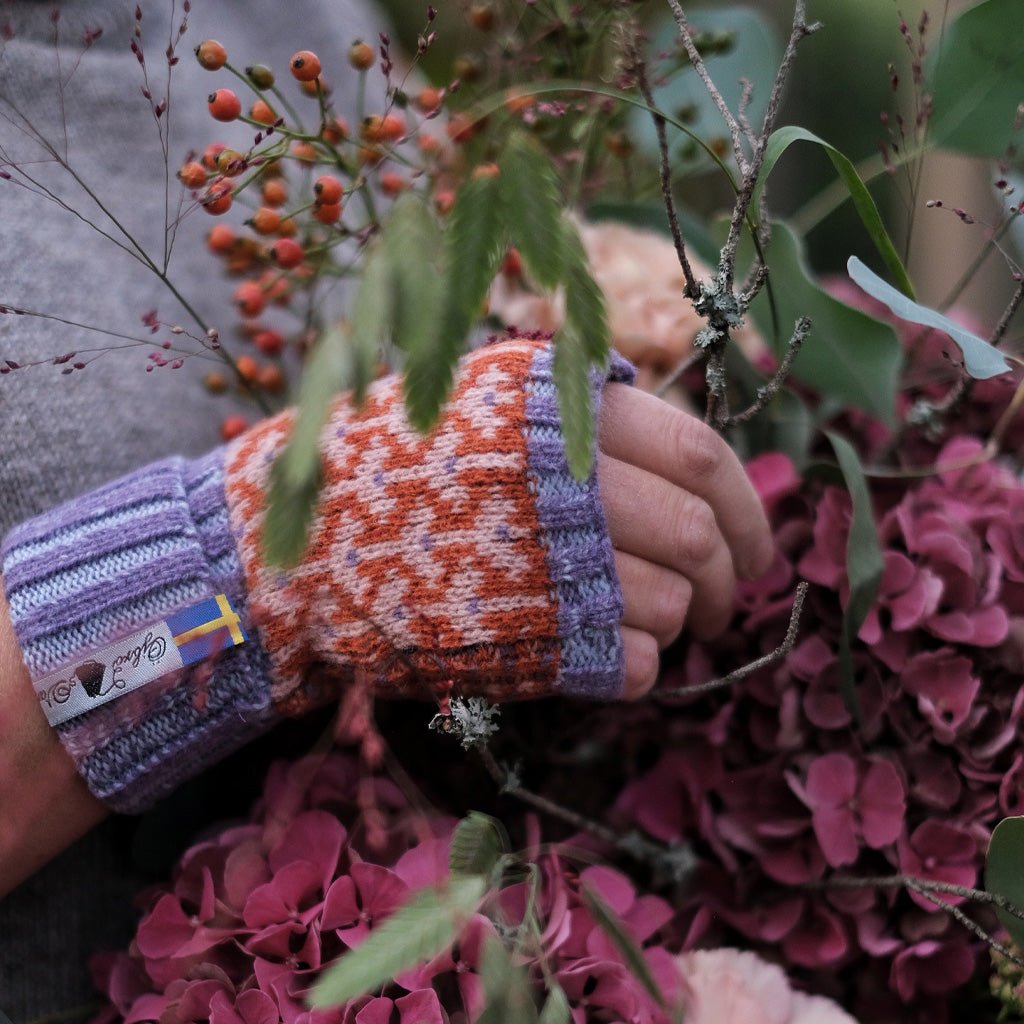 Hand wearing wool wrist warmers and holding flower arrangement.