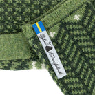 Close-up of green knitted wristwarmer with brand tag.