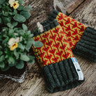 Pair of wool red and yellow wrist warmers on wooden table.