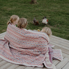 Group of kids wrapped in Lycksele wool blanket outside.