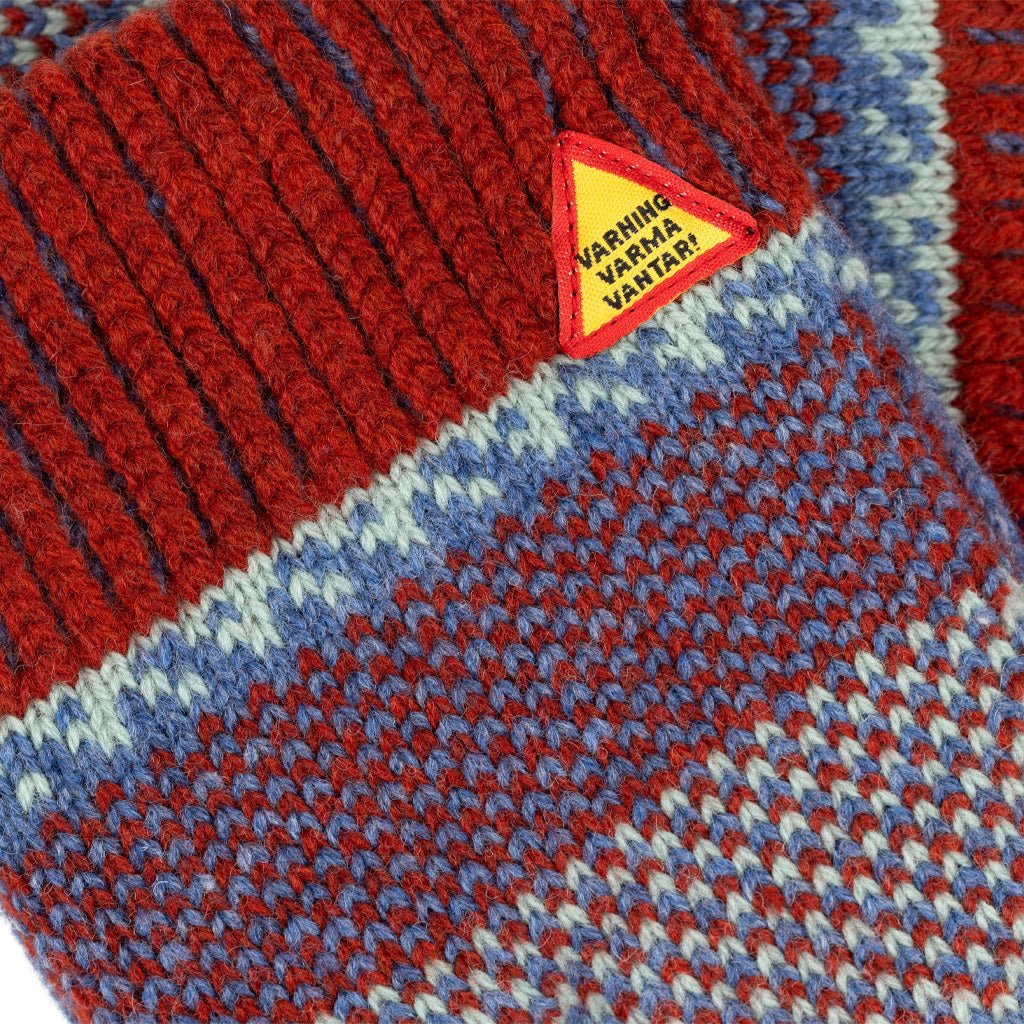 Close-up of warning label on red and blue wool mittens.