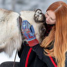 Woman wearing patterned wool mittens and petting animal.