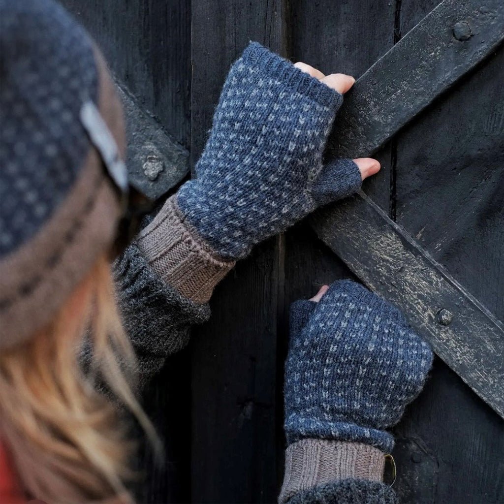 Person wearing wool wrist warmers in front of barn door.