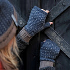 Person wearing wool wrist warmers in front of barn door.
