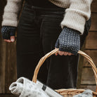 Hand wearing wool wristwarmer, carrying wicker basket.