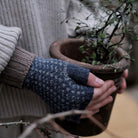Hand wearing wool wrist warmer, holding potted plant.