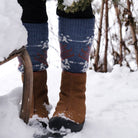 Model wearing blue wool socks and brown boots in snowy setting.
