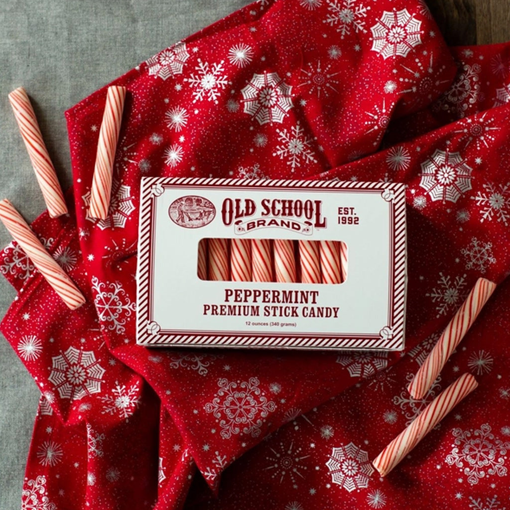 Box of peppermint stick candy on red blanket next to candies.