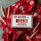 Box of peppermint stick candy on red blanket next to candies.