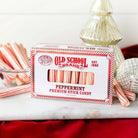 Box of peppermint stick candy in front of Christmas decorations.