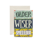 Greeting card reading “older wiser smellier” in bold, colorful lettering, shown with a cream envelope