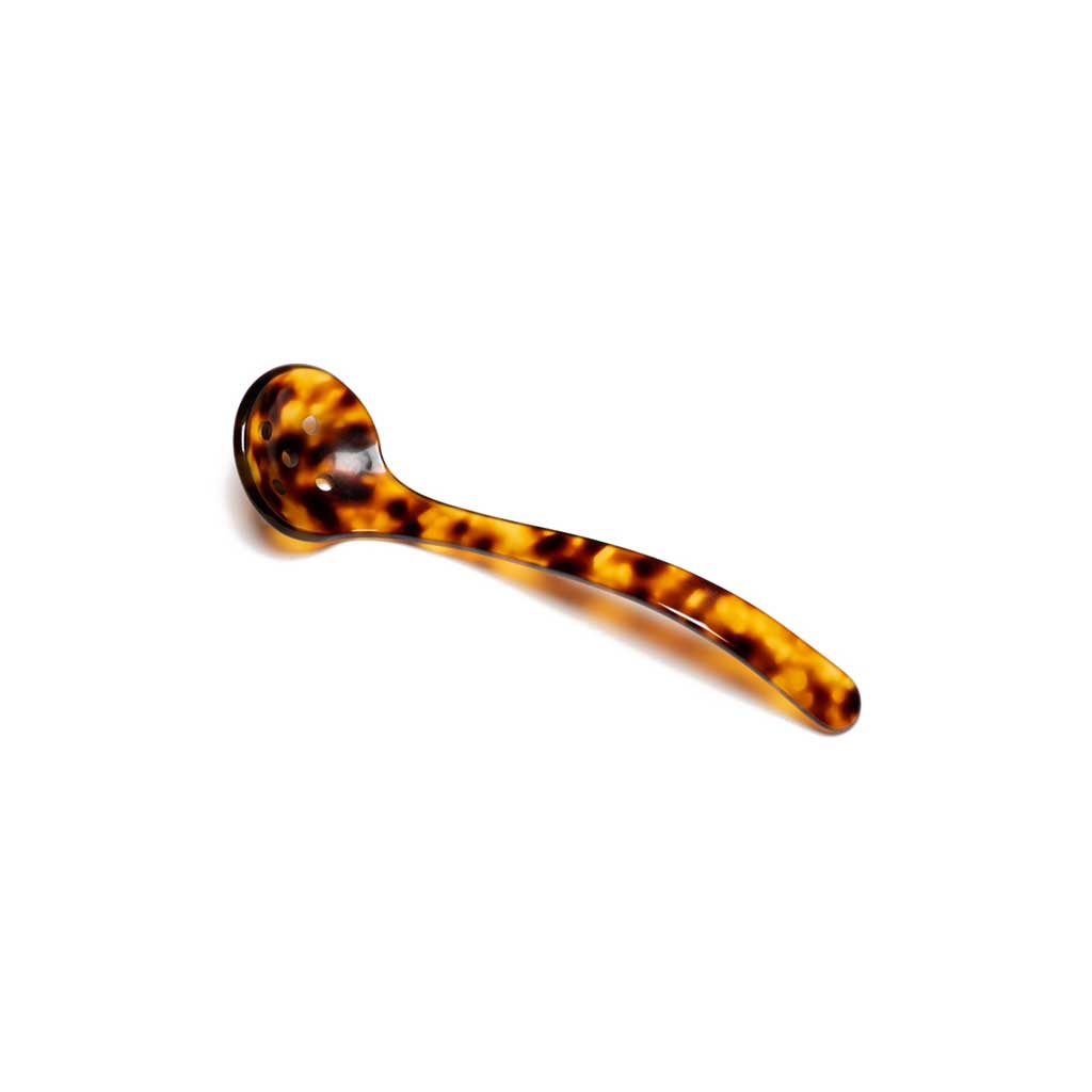 Tortoiseshell acrylic slotted spoon with curved stem on white background