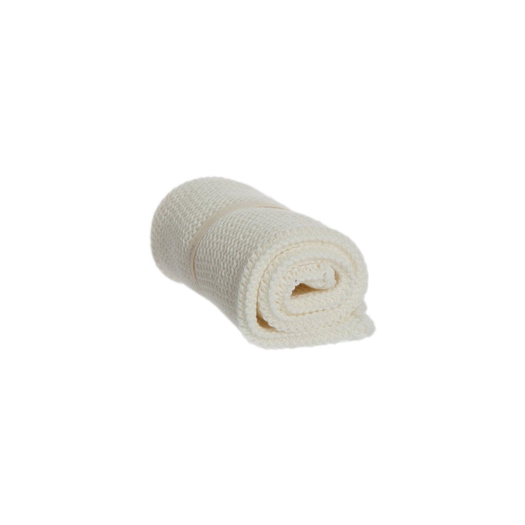 A rolled-up white knitted washcloth on white background